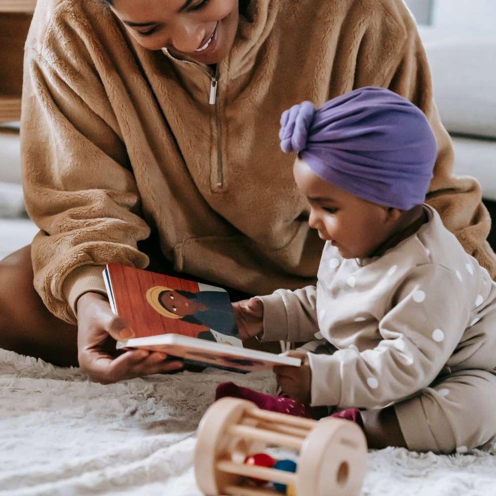 three books to read to your baby Mom reading a book to her baby board books as they explore books using their hands, gums, tongue, or teeth